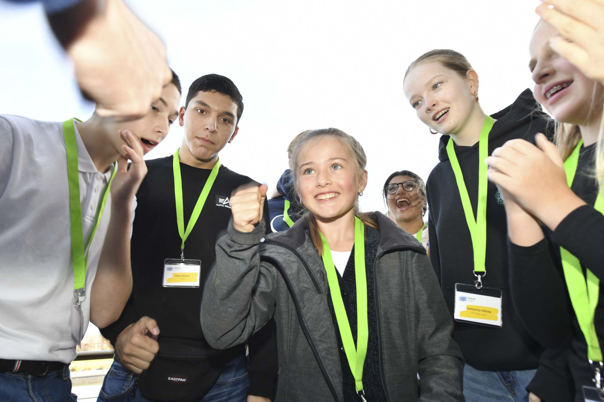 Jugendliche, die alle ein Namensschild an einem grünen Band um den Hals tragen, stehen in einer Gruppe zusammen