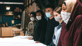Schülerinnen und Schüler mit Maske stehen in ihrer Werkstatt.